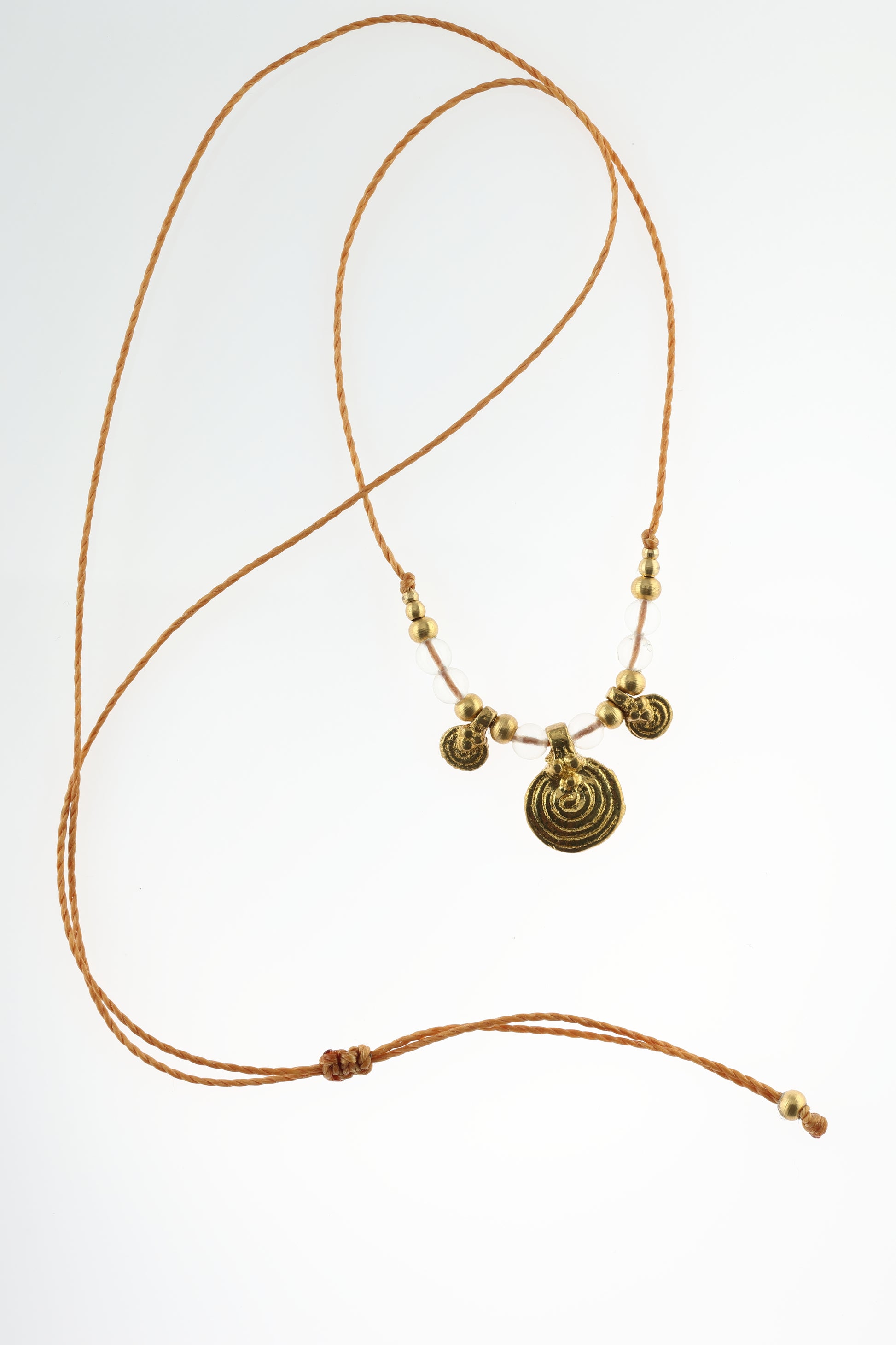 Halskette mit Edelstein- und Messingperlen sowie 3 runden Messinganhängern. Zentraler Messinganhänger mit Spiralsymbol. Kette aus beigem Makrameegarn. Stein und Farbe: Bergkristall –klar. Für Affirmation: „Ich bin im Jetzt“