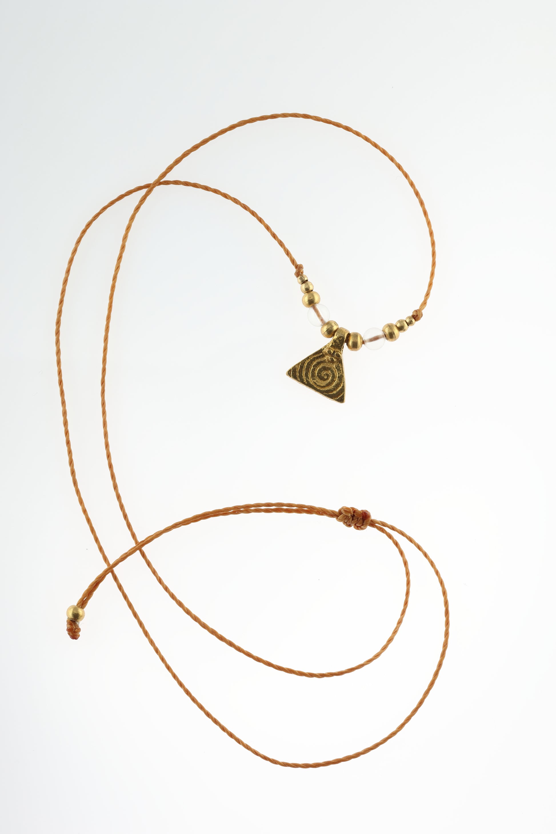 Halskette mit Edelstein- und Messingperlen sowie einem dreieckigen Messinganhänger mit Spiralsymbol. Kette aus beigem Makrameegarn. Stein und Farbe: Bergkristall – klar. Für Affirmation: „Ich bin im Jetzt“