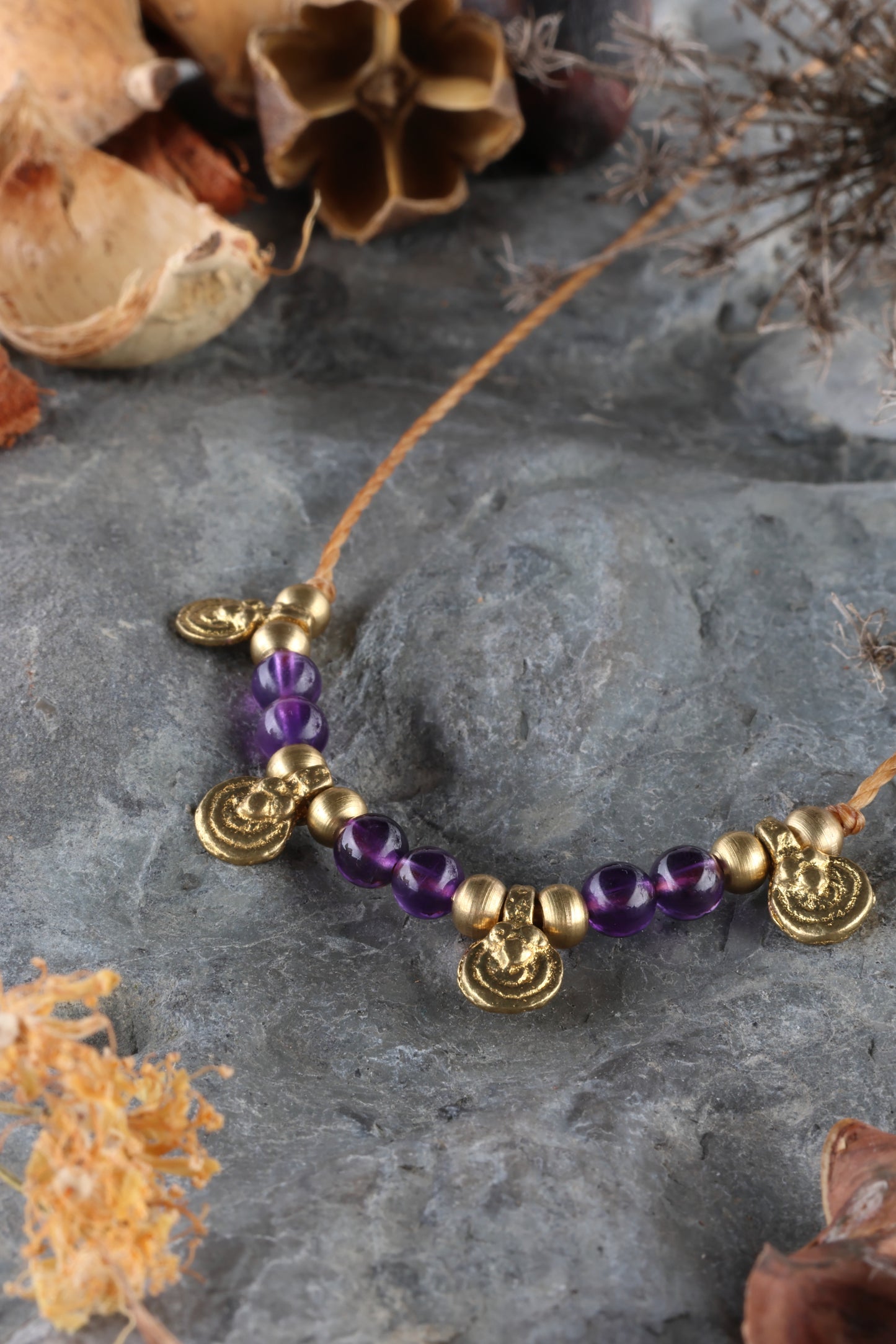 Halskette mit Edelstein- und Messingperlen sowie 4 kleinen runden Messinganhängern. Kette aus beigem Makrameegarn. Stein und Farbe: Amethyst – lila/klar. Für Affirmation: „Ich bin easy“